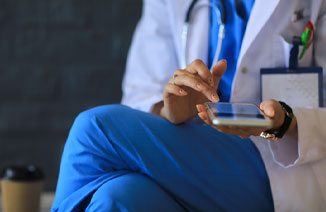 Young woman doctor sitting with phone